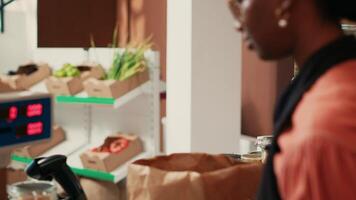 Woman waiting to pay for organic products at checkout, vendor putting all the items on electronic scale to ensure the right price value. Merchant helping client to buy natural eco friendly food. video