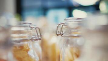 Selective focus of reusable jars filled with cereals and pasta to help with low carbon footprint. Eco friendly supermarket with ethically sourced grains and spices. Tripod shot. Close up. video