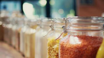 Various pasta types and grains stored in reusable jars and selling as bulk products, merchandise at zero waste natural store. Environmentally friendly supermarket. Handheld shot. Close up. video