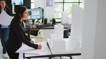 Architekten Mannschaft studieren 3d gedruckt Gebäude Modell- im Büro, suchen beim Rahmen und Gliederung zu verraten Fußboden planen Messungen. kreativ Agentur Angestellte Arbeiten mit architektonisch Blaupausen. video