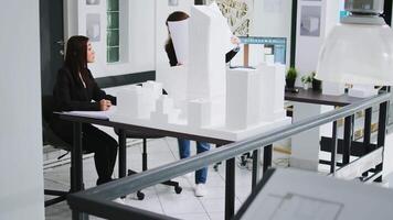 desenvolvimento funcionários produz plano para interior Projeto dentro agência ambiente de trabalho, estimando 3d impresso estrutura Tamanho e especificações. engenheiros usar maquete para rastrear dimensões do real configurações. video