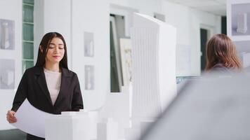 arquitecto analizando planos y 3d edificio modelos a diseño mesa, molesto a desarrollar nuevo industrial plan para residencial zona proyecto. mujer medición el dimensiones y elementos. video