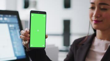 architetto Tenere smartphone con schermo verde disposizione su Schermo, Lavorando a un' vero tenuta agenzia ufficio. donna specialista utilizzando chiave cromatica modello su isolato modello schermo, copyspace concetto. video