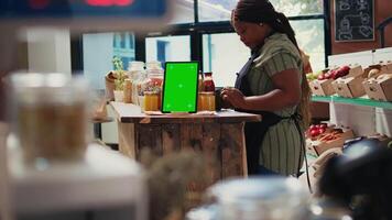 Digital layout of greenscreen on tablet placed in farmers market, display showing blank copyspace screen next to women talking about additives free bulk items. Isolated mockup template. Tripod shot. video