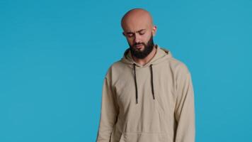 Young adult gesturing no over blue background, posing in studio and expressing negative reaction. Middle eastern person doing rejection symbol, showing his refusal and denial. Camera 1. video