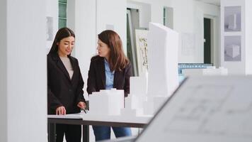 diseñadores dar un alto cinco después redacción objetivos, satisfecho con su esfuerzos en mudado dimensiones y decidiendo escalada componentes para construcción. mujer terminar asignaciones correctamente. video