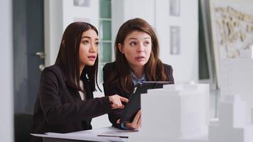 Specialists taking notes on tablet after reviewing building model, trying to capture accurate dimensions of physical spaces. Developers planning and designing architectural project. video