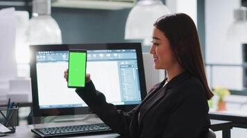 Developer shows mobile phone with greenscreen template, working in small business coworking space. Engineer using isolated copyspace layout on blank mockup screen, chromakey background. video