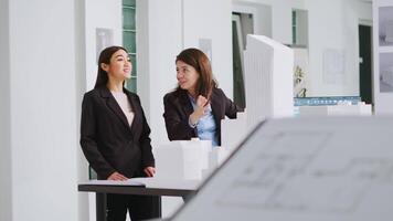 Architects doing high five gesture after finishing blueprints, feeling happy about translating measurements and determining scale elements for building development. Women solve task successfully. video