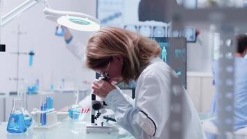 boneca tiro do equipe trabalhando dentro moderno Alto fim laboratório. uma fêmea químico é analisando alguns amostras video