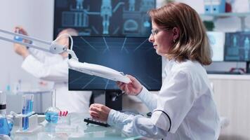 Working in modern and well equipped laboratory. Women scientists in laboratory analyse a sample using a big industrial magnifying glass video