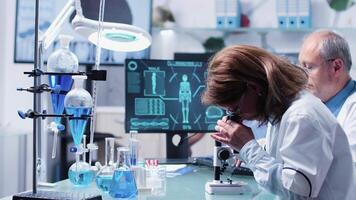 Female and male scientists working in modern laboratory, debating over some blue samples video