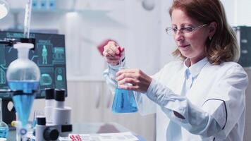 Female researcher takes samples from a tube. In the background - modern laboratory video