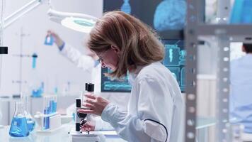 Female researcher taking notes in a clipboard. In the background - an active team is working in modern laboratory video