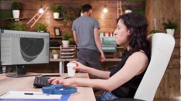 vrouw ontwerper toepassingen professioneel 3d software toepassing naar werk Aan nieuw wind turbine prototypen. in de achtergrond - bezig en creatief media agentschap huis video