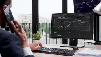 Revealing shot of businessman working on the computer in modern office with big windows. Display shows sales statistics video