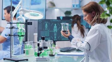 Female biologist looking at plant samples and taking notes in a clipboard. Modern professional biochemistry laboratory video