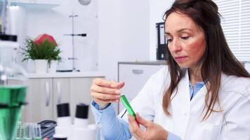 Portrait of female bio researcher looking at green samples video