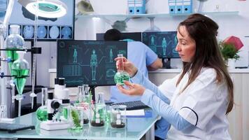 Female chemist researcher testing some green samples in modern laboratory video