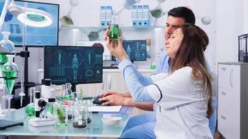Bio researcher looking at samples and talking with her assistant in modern laboratory. Zoom in slow motion shot video