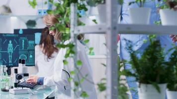 occupé journée dans botanique laboratoire. scientifiques sont travail sur le ordinateur et en utilisant le microscope video