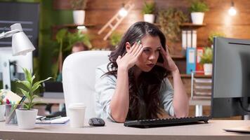 Stressed woman having a headache while working in the office. Exhausted and overworked girl. Busy team in the background. video