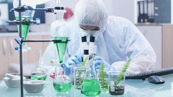 Close up shot of biotechnologist desk with test tubes and samples. He is looking under the microscope video