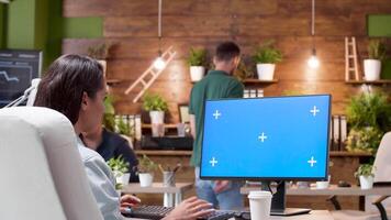 Wide shot of a woman working on a computer with isolated mock-up in a busy office video