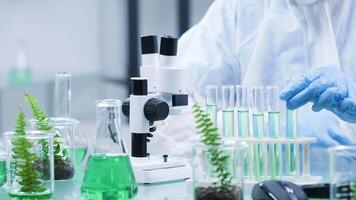 Close up shot of biochemist desk. It is covered with test tubes and he looks under a microscope video