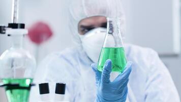 Biotechnologist looking at a sample with green liquid. Researcher and analysis video