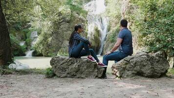 joven hermosa Pareja admirativo un cascada. turismo y viaje video