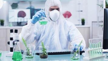 Scientist in coverall analyzing different samples in modern laboratory video