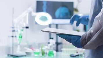Chemist typing on a digital tablet PC while wearing gloves in modern high-end laboratory video