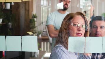 Young team paying attention to their leader for fresh ideas. Writing on sticky notes. Creative workplace. video