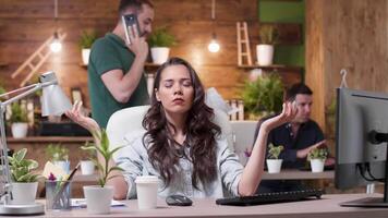 Woman meditates while her colleagues are throwing papers in the air in a very stressed work environment. Slow motion shot and conceptual footage video