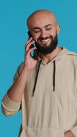 Vertical Video Arab person answering phone call in front of camera, talking to his friends on remote chat with smartphone. Young adult using mobile phone communication to discuss with people. Camera 1.