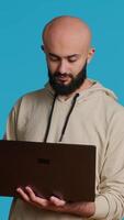 Vertical Video Middle eastern man works with cyber security on laptop, trying to do some software programming and report bugs. Young adult operating as a system developer in studio. Camera 1.