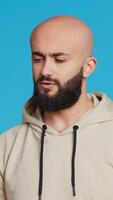 Vertical Video Young guy gesturing no sign over studio background, posing in studio and showing negative emotion. Middle eastern model doing forbidden gesture, expressing his refusal. Camera 2. Handheld shot.