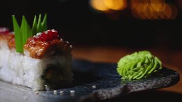 Close-up of beautifully decorated sushi rolls on plate with wasabi. Frame. Professionally prepared and decorated sushi rolls with eel in expensive restaurant video