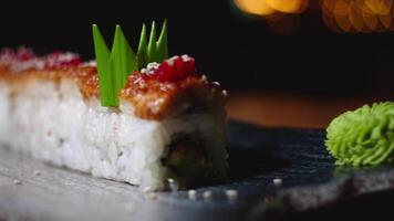 Close-up of beautifully decorated sushi rolls on plate with wasabi. Frame. Professionally prepared and decorated sushi rolls with eel in expensive restaurant video