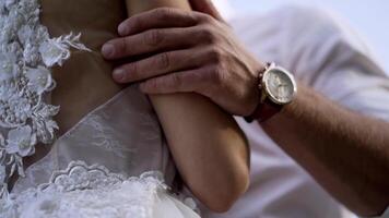 Close-up of husband's hands hugging wife. Action. Husband gently touches his wife's waist in white wedding dress. Concept of wedding video