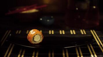 Close-up of sushi roll on plate. Lonely sushi roll with salmon and cheese is on black plate, which takes hand in black glove video