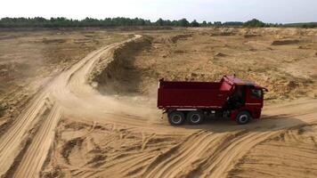 cumulo di rifiuti camion su Aperto fossa strada. scena. superiore Visualizza di cumulo di rifiuti camion guida su argilla strada cava nel campagna con foresta su orizzonte video