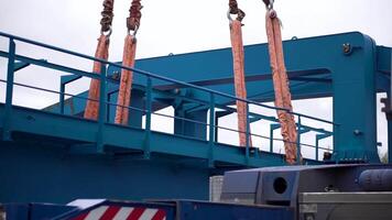 Crane lifts heavy iron detail. Clip. Industrial iron large metal gantry crane with a hook mounted on the supports for lifting and carrying heavy cargo, moving along the rails at the factory. The crane video