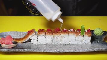 Chef decorating sushi rolls for serving in restaurant. Frame. Close-up of professional chef sprinkles sesame on sushi roll with eel for beautiful serving video