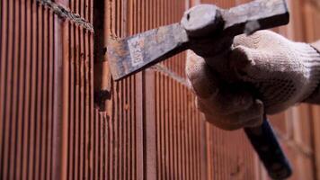 Worker hammering ceramic blocks to make a slotted hole. Stock footage. Building and construction concept, man with metal hammer while house building. video