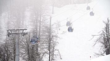 Winter ski resort with ski lifts on mountain. Ski slope with ski lifts and runs in foggy weather. Active holidays in winter video