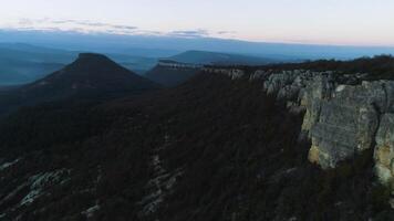 Matin Montagne paysage avec vagues de brouillard. tir. Haut vue de montagnes dans brouillard et Roche à crépuscule. mystique brumeux paysage de rochers et montagnes avec forêt couverture dans semi-obscurité de crépuscule video