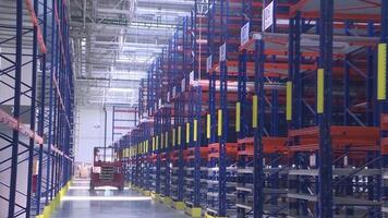 Large storage room with vertical storage. Scene. High storage racks, bottom view, concrete floor, a huge room with red and blue shelves. Storage room in a huge factory video