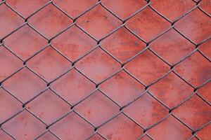 Chain link fencing mesh or wire gauze and red painted metal with rusty on surface background. photo